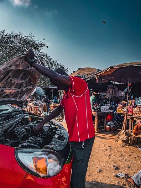 Mécanicien travaillant sur une voiture dans un marché en plein air africain
